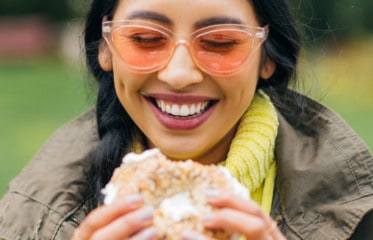 woman smiling eating a bagel with cream cheese