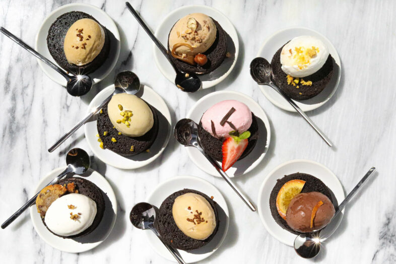 Eight ice cream and chocolate cakes with spoons.