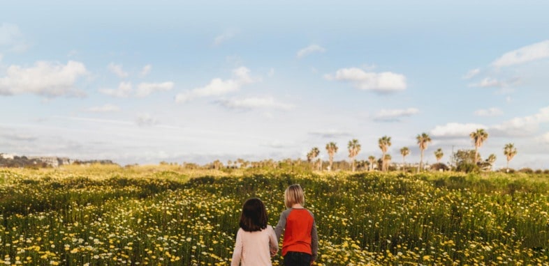 two children walking through a flower field